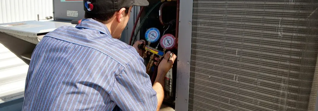 HVAC technician servicing a condenser unit in Mexico
